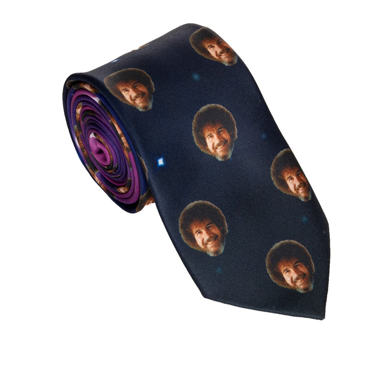 Officially Licensed Bob Ross "Faces" Necktie Full Photo Of Tie Up Close Rolled Up With All Over Bob Ross Faces Print On Dark Backing 
